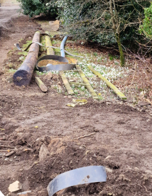 Pieces of wood and metal lie on top of an area of snowdrops, crushing them