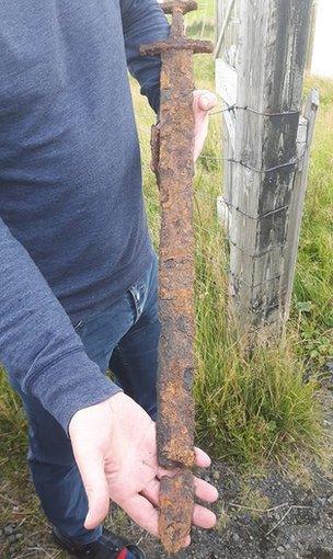 A close-up of the sword being held by one of the men