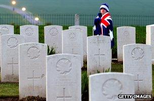 Child wearing Australian flag walks past graves at Australian war memorial in France