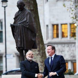 Prime Minister David Cameron (R) with Indian Prime Minister Narendra Modi (L) stand in front of the Gandhi statue in Parliament Square in London