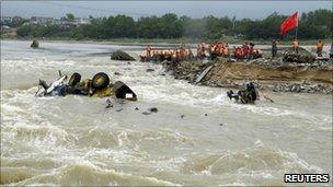 Policemen work on the breached dyke in Qingcao town, Anhui, on 13 July 2010