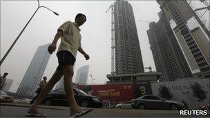 Man walks past tall buildings in China