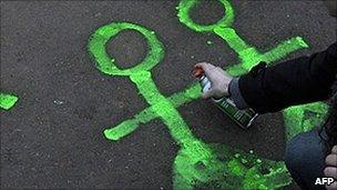 Person spray paints a symbol of a homosexual couple