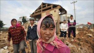 Villagers stand in front of their houses destroyed by floods in Yunnan province