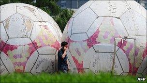 A man walks past giant footballs in Beijing, China (23/06/2010)