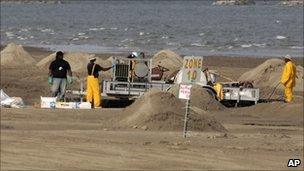 Workers cleaning up the beach on Grand Isle, Louisiana, on 16 July