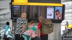 Travellers at airport departures board