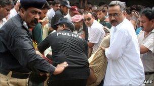 Security officials carry the bodies of two Christians killed outside a court in Faisalabad on 19 July 2010