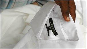 A man lifting a shirt to show a George label on the collar