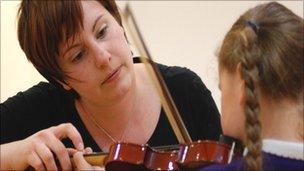 Young girl being taught violin