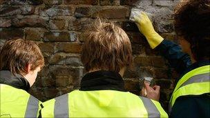 People scrubbing graffiti from a wall