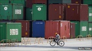 A man walks past a pile of containers at a container yard near a port in Tokyo