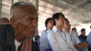 Elderly man watches the verdict with school-age children in Phnom Penh