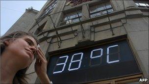 A Russian woman wipes her forehead under a temperatre sign reading 38C (100F) in Moscow, 29 July 2010