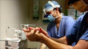 Surgeons scrubbing up before performing an operation in an NHS hospital