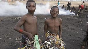 Greenpeace photo of boys with a bundle of electrical cables and other electronic components in Accra, Ghana, 2008. The cables are burned to extract the copper, a process that releases toxic chemicals into the environment.