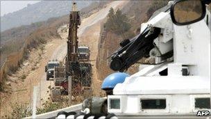 UN troops observe an Israeli military bulldozer along the border with Lebanon, 4 August