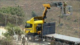 Israeli soldiers use a crane as they appear to cut down a tree on the Lebanese side of the fenced border, near the village of Adaysseh on 3 August.