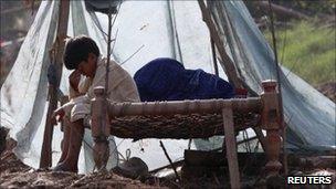 A boy sit on a bed in ruin on family home in Pabbi, north-west Khyber Pakhtunkhwa province, on 5 August 2010
