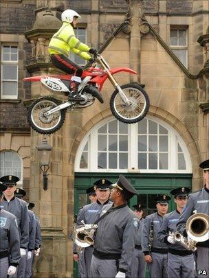 Lee Lucas, 16, of the IMPS motorcycle display team, jumps over Second Lieutenant Miles Evans, 21, and other members of the Citadel Military College of South Carolina Band and Pipes at the Redford Barracks in Edinburgh ahead of the Royal Edinburgh Military Tattoo.