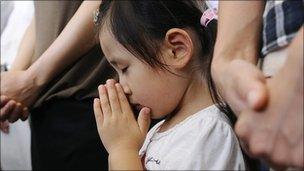 A girl offers a prayer during a ceremony to mark the 65th anniversary of the Nagasaki bomb attack