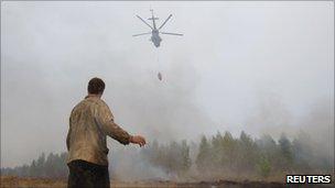 A man watches as a helicopter dumps water on a blaze in Russian's Ryazan region, 9 August