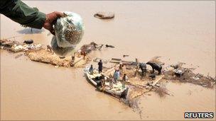 Families receive relief supplies from an army helicopter
