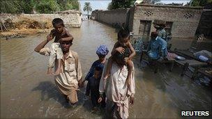 A family wades through waters in the village of Karam Pur near Sukkur in Sindh province