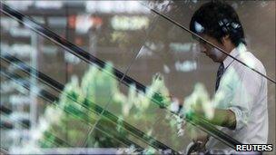 A man in Japan while a graph of the Yen against the US dollar is reflected