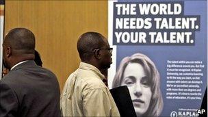 Francis Didier of Miami, right, stands in line to see representatives from Kaplan University at a job fair sponsored by National Career Fairs in Dania Beach, Fla