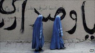 Afghan women pass a parliamentary elections graffiti in Mazar-i-Sharif on 22 July 2010