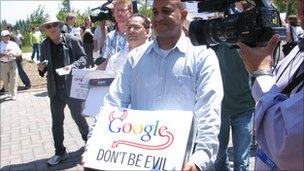 guy carrying a box of petitions with Google don't be evil sign