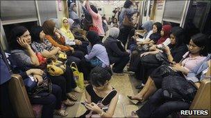 Women board a women-only carriage of a commuter train in Jakarta