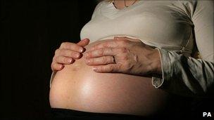 A pregnant woman holding her stomach