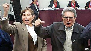 Shining Path leaders Elena Iparraguirre and Abimael Guzman raise their fists after their trial was deferred on 5 November 2004.