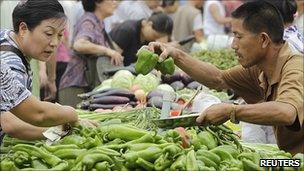 Customers select vegetables at a market in central Beijing