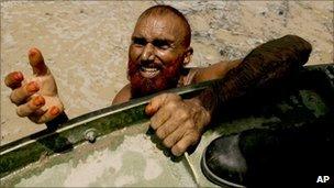 A Man hangs of the side of a military hovercraft near Sukkur Pakistan