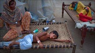 8 year old Yakub, suffering from Diarrhea lays on a bed next to his mother as he receives medical care at a makeshift hospital on August 22, 2010 in Muzaffargarh in Punjab