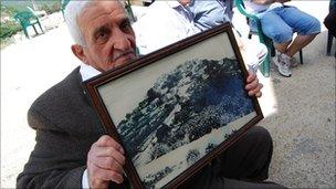 Displaced Palestinian from Iqrit, in northern Israel, holding up a photo of the village