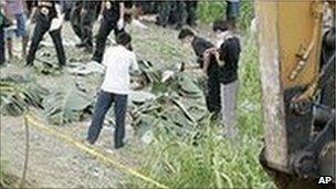 Police inspect the bodies in hillside grave in Ampatuan, Maguindanao province