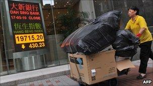 A cleaner walks past a display showing the Hang Seng index in Hong Kong on 21 May 2010