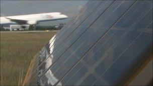 Plane landing behind solar panels