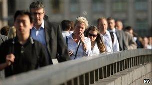 Commuters cross London Bridge on their way to work in the City financial district of London