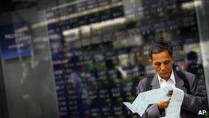A man shuffles papers outside a securities" firm in Tokyo