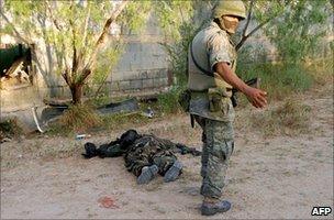 Mexican soldier standing next to dead body