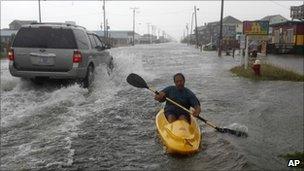 A man kayaking on a flooded street in North Carolina