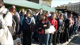 Commuters wait for a bus