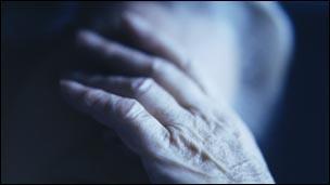 Elderly woman with her head in her hands