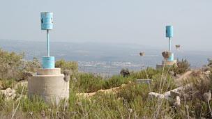 Painted oil barrels perched atop a solid concrete base along the border