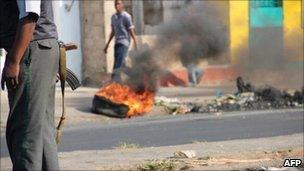 A Mozambican policeman stands near a burning tyre on a street of Maputo, 02/09
